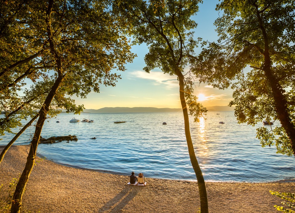 Ein atemberaubender Sonnenuntergang durch die Bäume am Strand in der Nähe des Veya Maradiso Hotels von Aminess.
