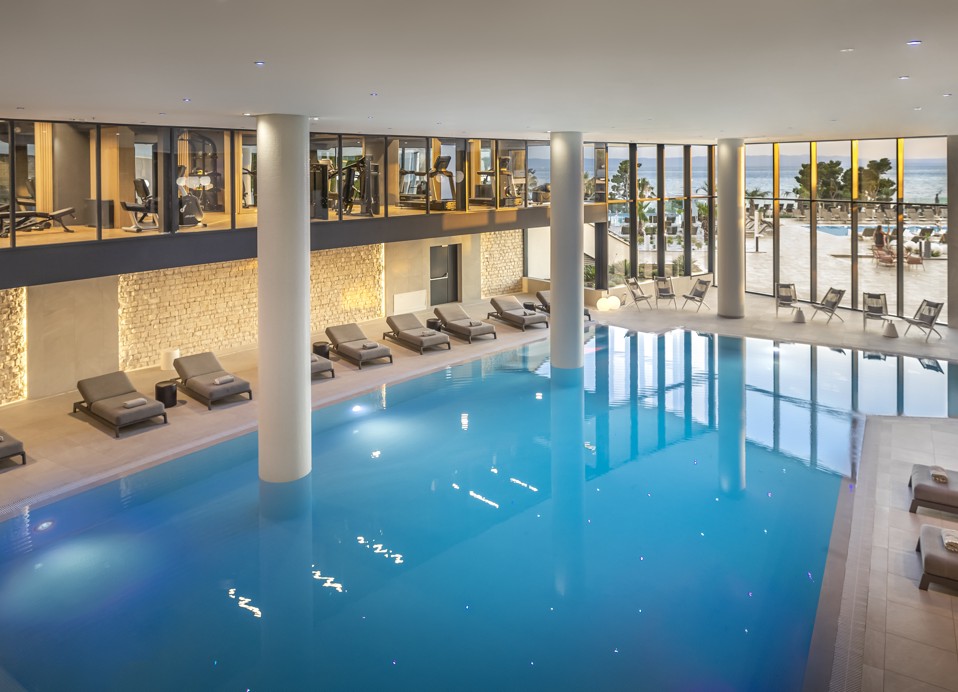 Piscina interna moderna con vista sulla palestra e sui lettini nell'hotel Aminess Laurel Khalani.