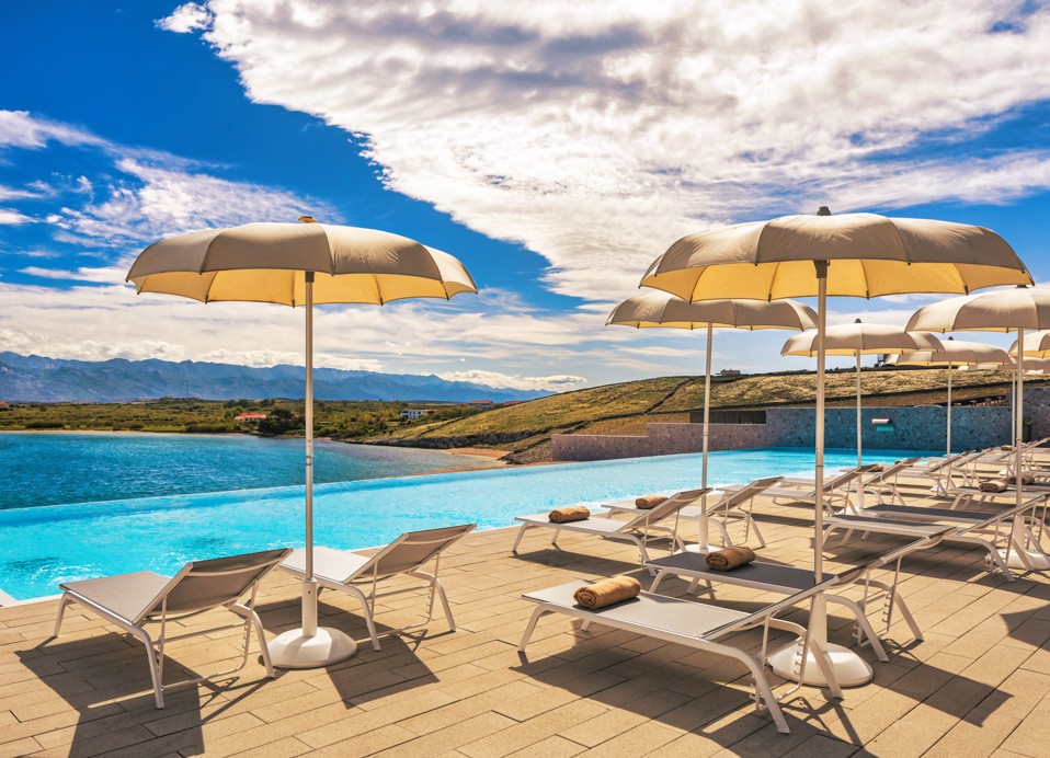 Liegestühle und Sonnenschirme neben dem Entspannungspool im Aminess Style Camping Avalona Resort aufgereiht.