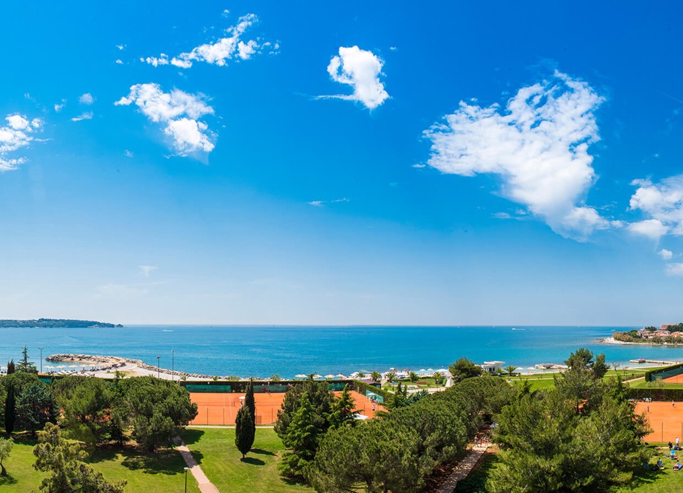 Luftaufnahme der Tennisplätze im Aminess Planet Camping Sirena in Novigrad, Kroatien, mit der umliegenden Landschaft und dem Meer in der Ferne