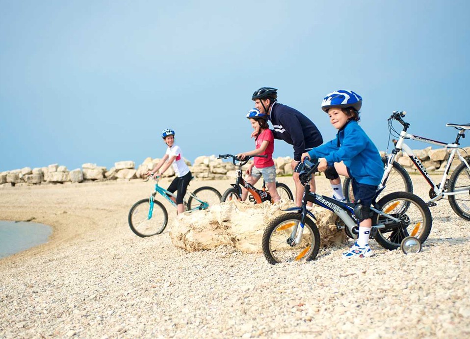 Gezin op fietsen op een strand bij de Aminess Planet Camping Maravea, Novigrad