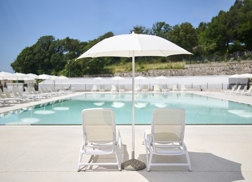 Außenpool des Hotels Aminess Lišanj mit Liegestühlen und Sonnenschirm, umgeben von Grün.