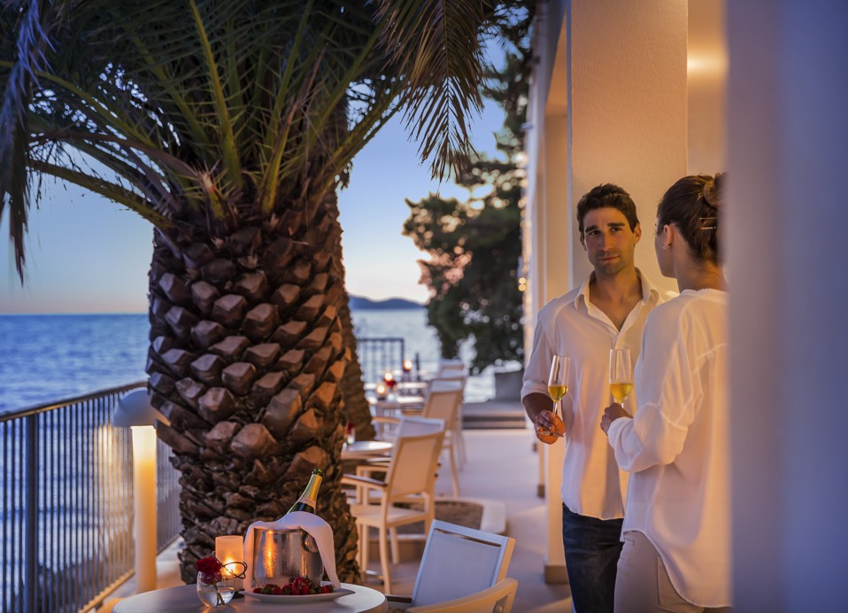 Paar entspannt bei einem Glas lokalen Weißwein auf der Terrasse der Seaside Bar im Aminess Younique Lume Hotel.