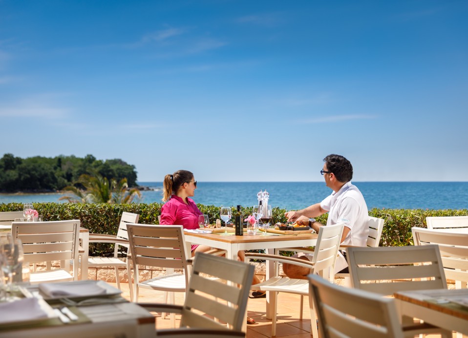 Paar genießt die Aussicht und das Essen auf der Terrasse des Restaurants Capa im Aminess Planet Camping Maravea Resort, Novigrad Kroatien