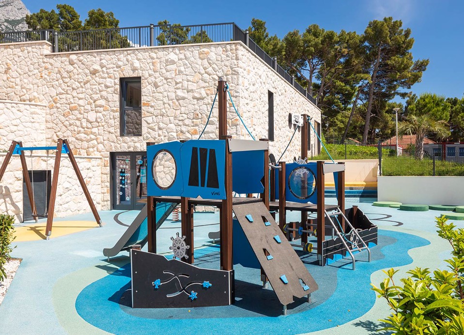 Outdoor-Spielplatz für Kinder mit Rutschen im Aminess Laurel Khalani Hotel.