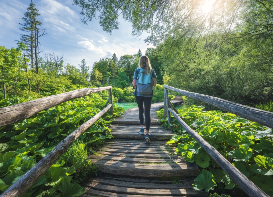Hiker walks along a wooden trail through green nature near Karlovac.