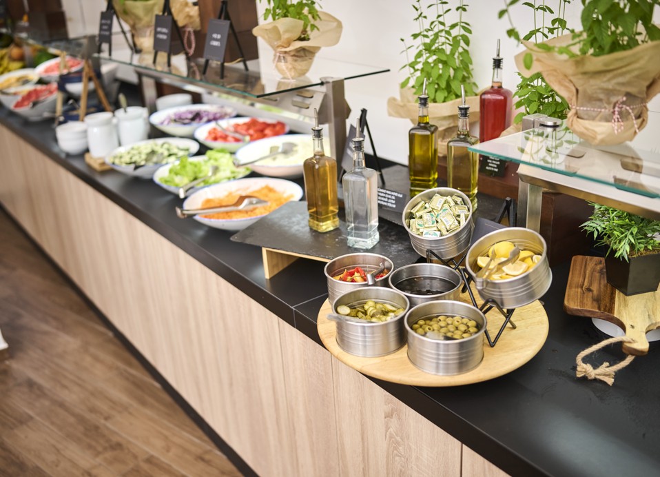 A vibrant buffet spread at Restaurant Rondela in Aminess Maradiso Casa Bellevue, featuring a variety of fresh fruits, vegetables, and delicacies on sleek wooden counters.