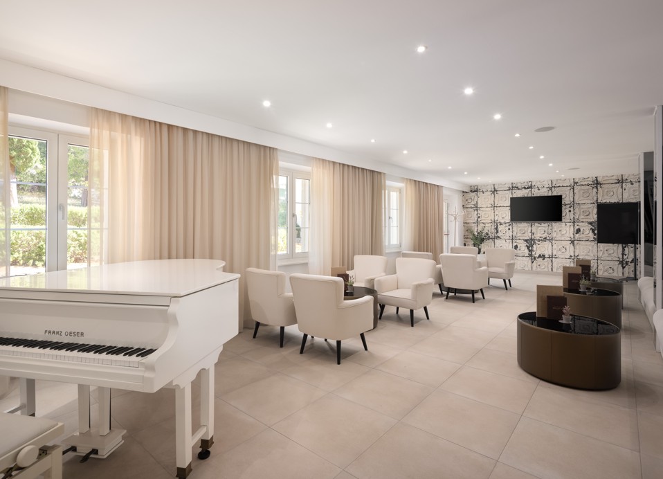 Bar Noir lounge at Younique Bellevue Hotel by Aminess with a white piano and armchairs.