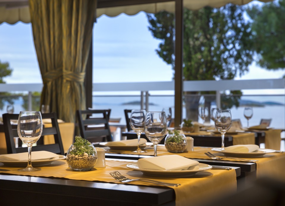 Esstische auf einer Terrasse mit wunderschönem Blick auf das Meer und die Natur im Aminess Vival Grand Azur Hotel.