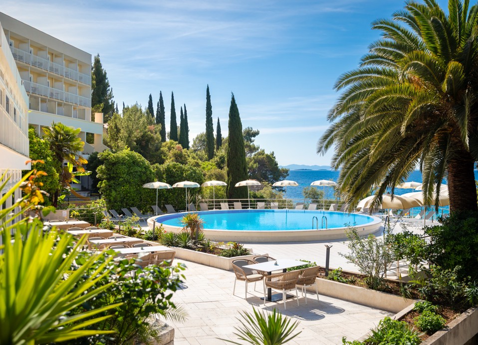 Pool im Orsan Maradiso Hotel by Aminess mit Palme und Meerblick.