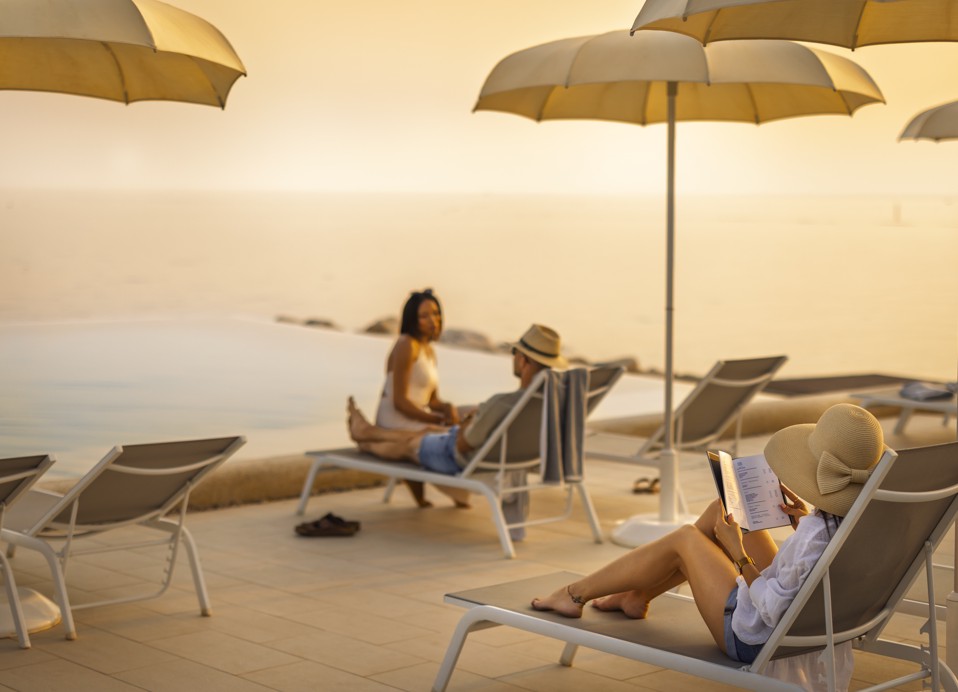 Person unwinding on a lounger by the infinity pool at sunset at Aminess in Novigrad, Istria.