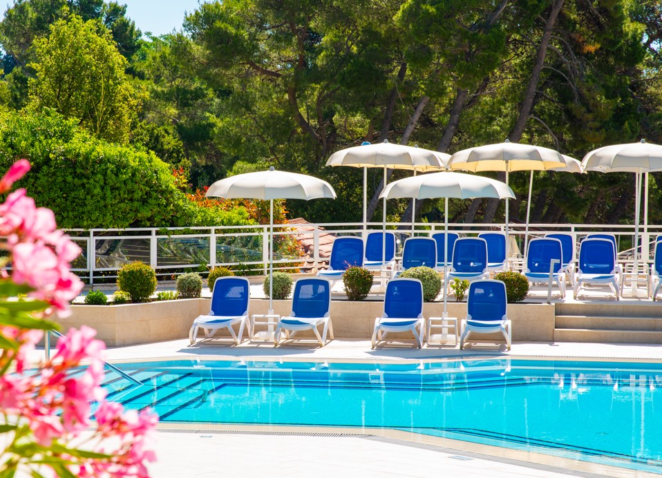 Blick auf den Pool mit Sonnenschirmen und Liegen vor dem Aminess Vival Grand Azur Hotel, Orebić.