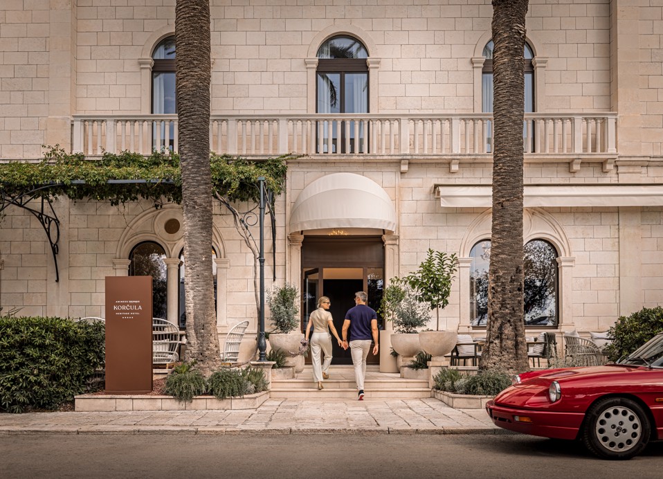 Para wchodzi do Younique Korcula Heritage Hotel przez kamienne wejście.