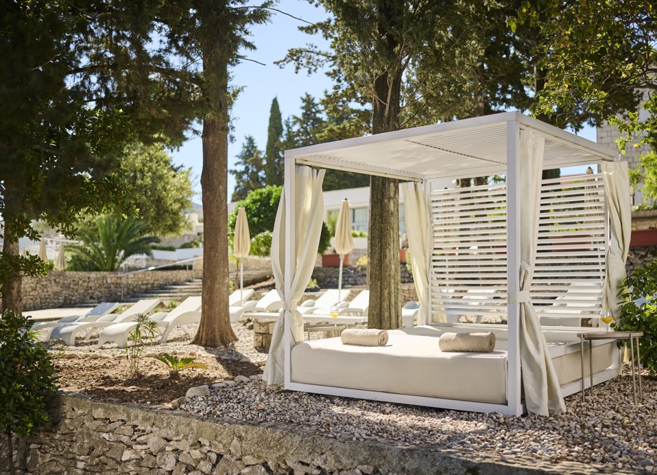 Baldachinbetten eingebettet in üppiges Grün, bieten eine ruhige und private Atmosphäre im Aminess Vival Port9 Resort in Korcula.