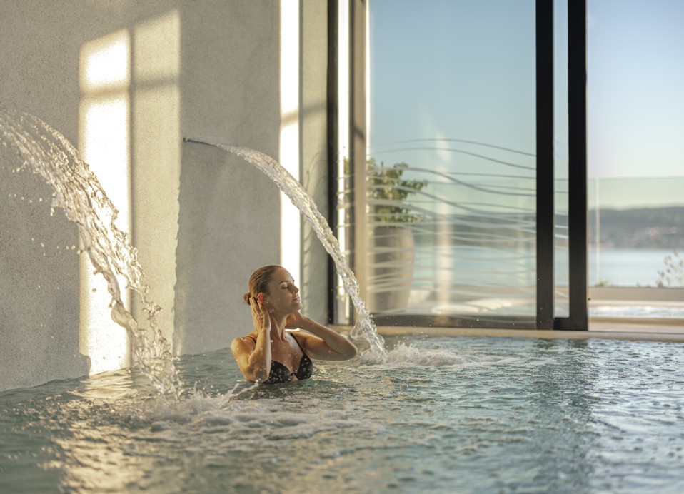 Donna che si gode una rilassante cascata nella piscina presso l'Aminess Younique Narrivi Hotel.