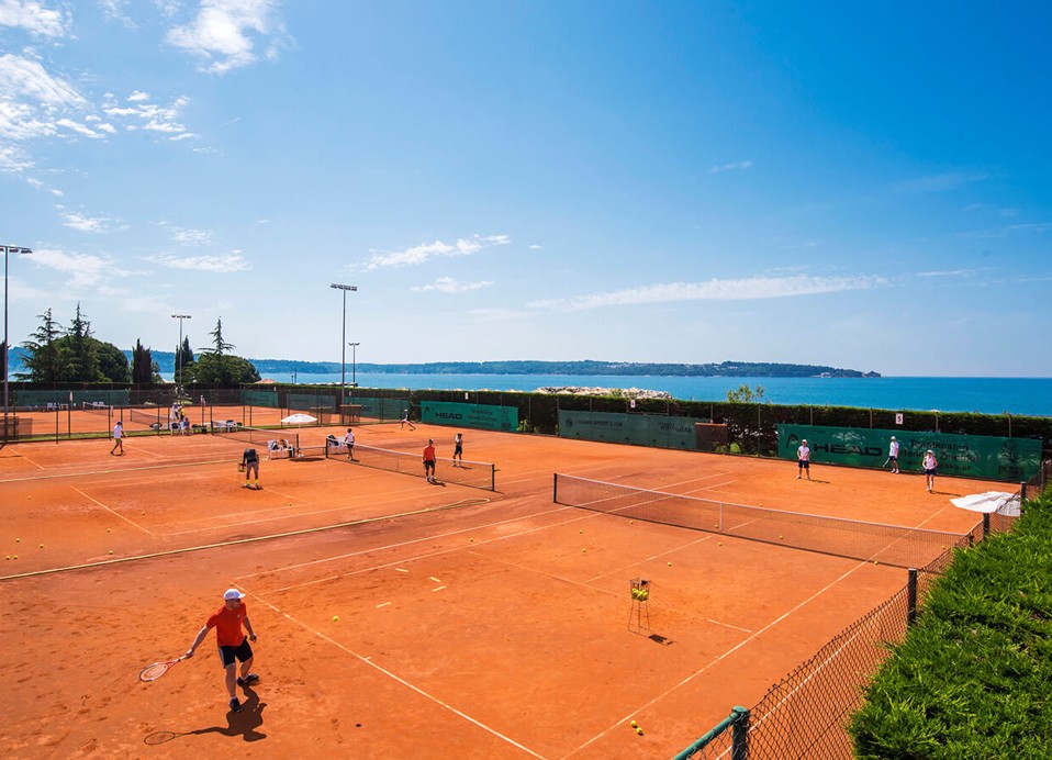 Tennisplätze im Aminess Planet Camping Sirena in Novigrad, Kroatien, mit Blick auf das Adriatische Meer im Hintergrund
