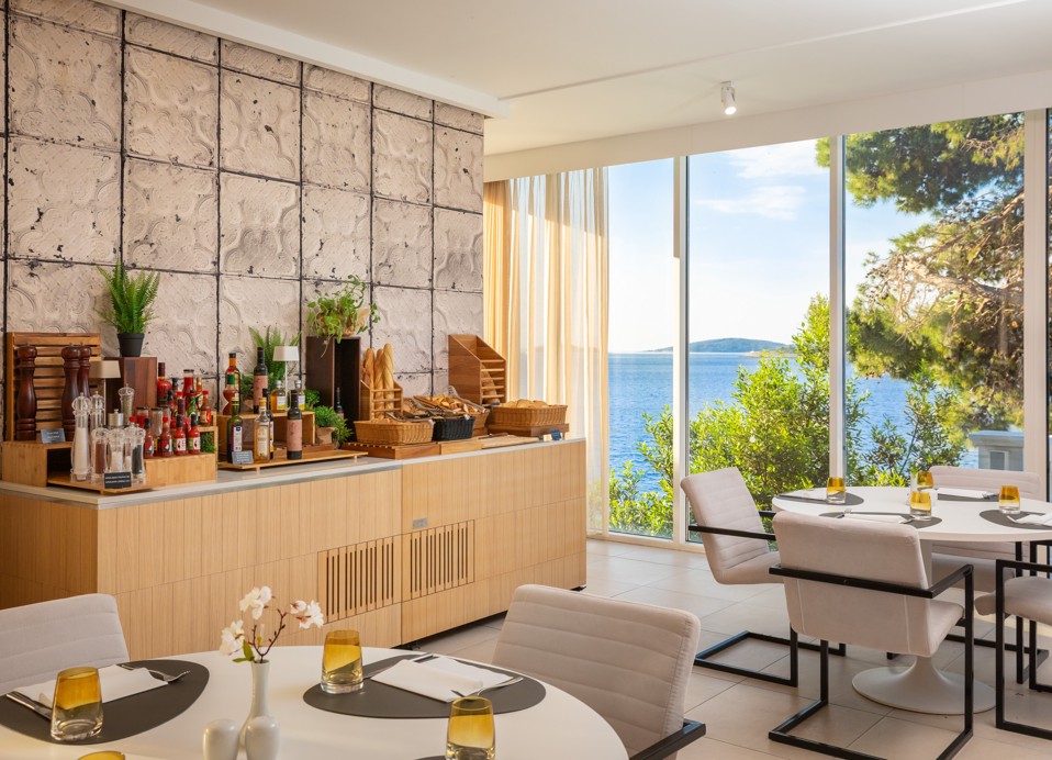 Restaurant at Younique Bellevue Hotel by Aminess with set tables and a sea view.