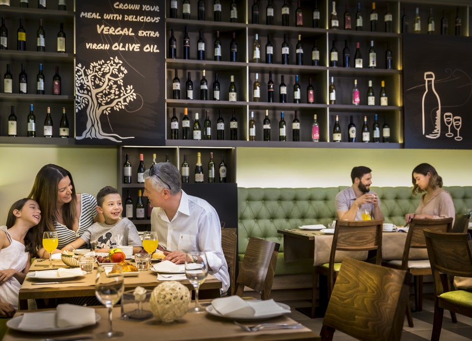 Een gezin dat ontbijt in het Ventola restaurant, met een stel op de achtergrond.