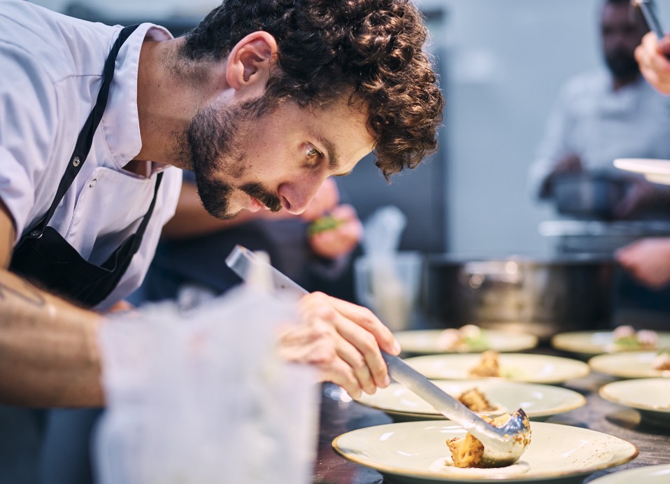Chef che impiatta con precisione un piatto durante Aminess Wine & Gourmet Nights, attenzione alla tecnica fine dining