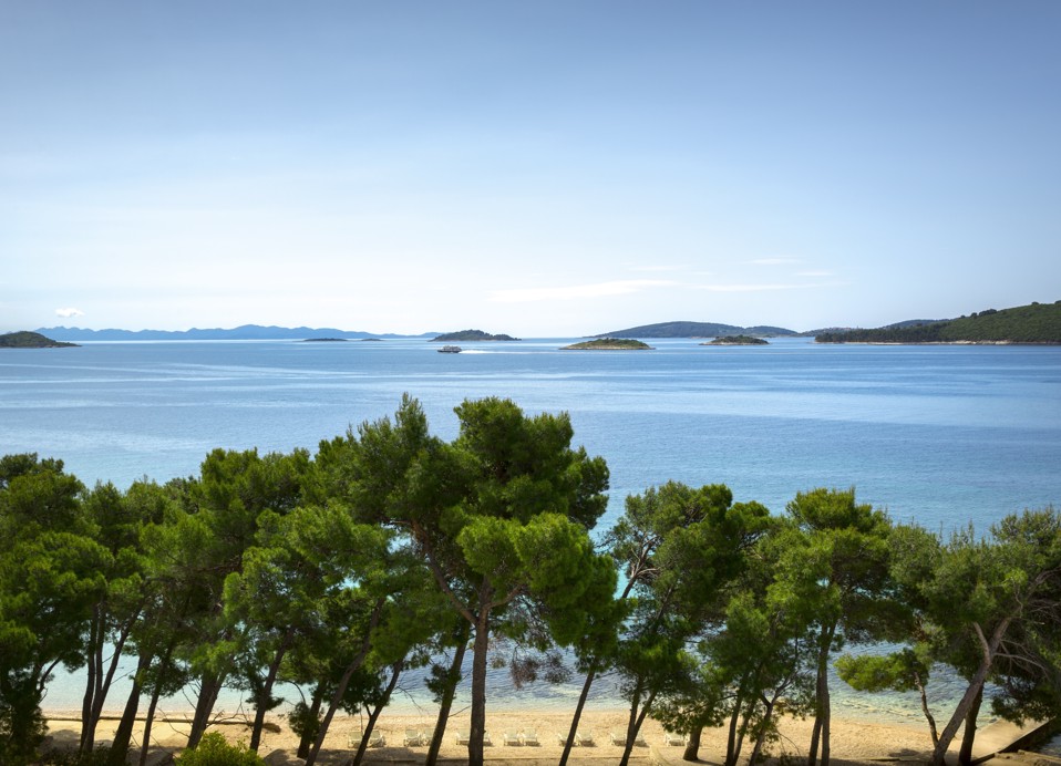 Blick auf einen ruhigen Strand, der von Pinien in der Nähe des Aminess Vival Grand Azur Hotels in Orebic beschattet wird.