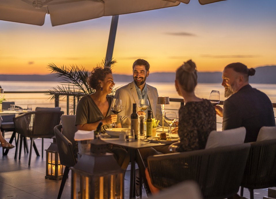 Prijatelji uživaju u očaravajućoj večeri uz slikoviti zalazak sunca u 7 Seas Restaurant & Bar-u blizu Veya Maradiso hotela by Aminess.