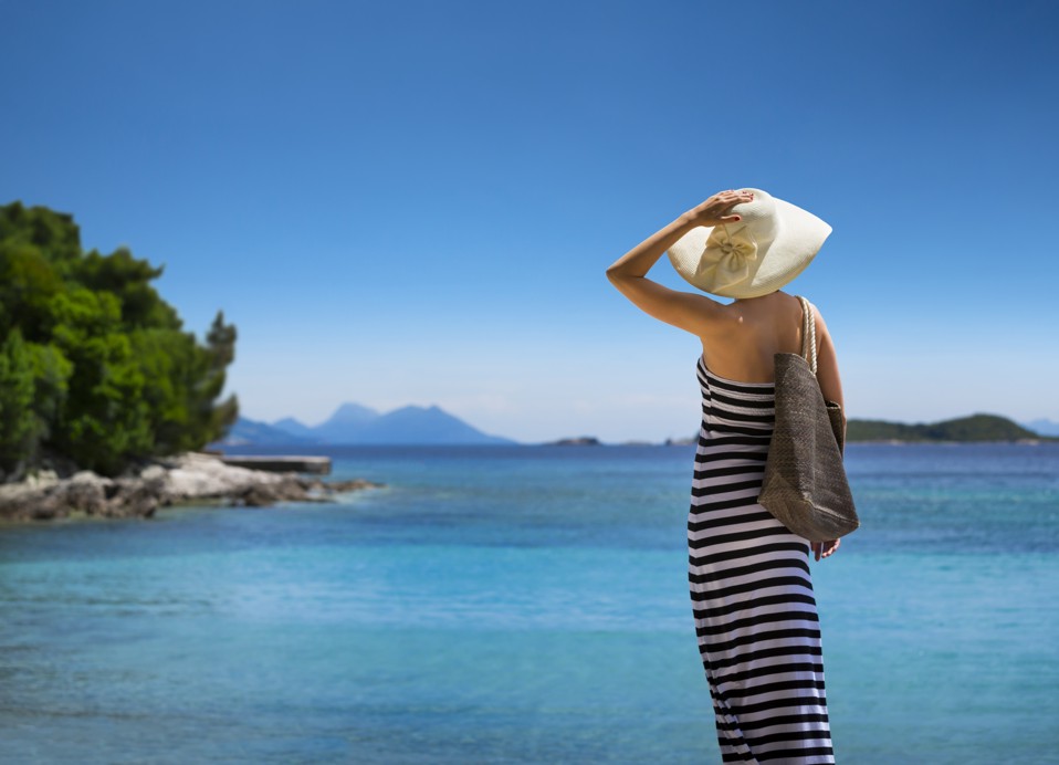 Frau mit Sommerhut bewundert den atemberaubenden Strand- und Meerblick in der Nähe des Aminess Vival Grand Azur Hotels.