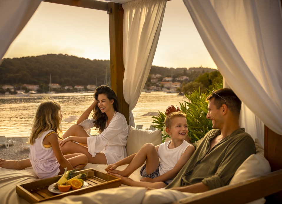 Eine Familie entspannt gemeinsam auf einem Himmelbett und genießt die wunderschöne Landschaft im Aminess Vival Port9 Resort in Korcula.