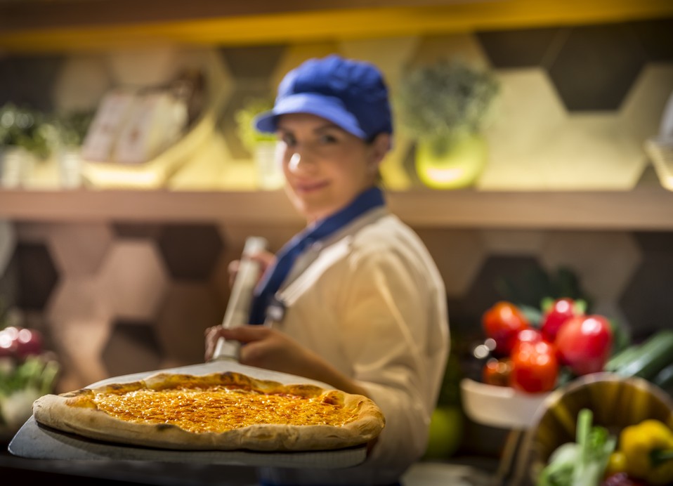 Pizzabakker haalt een pizza uit de houtgestookte oven.