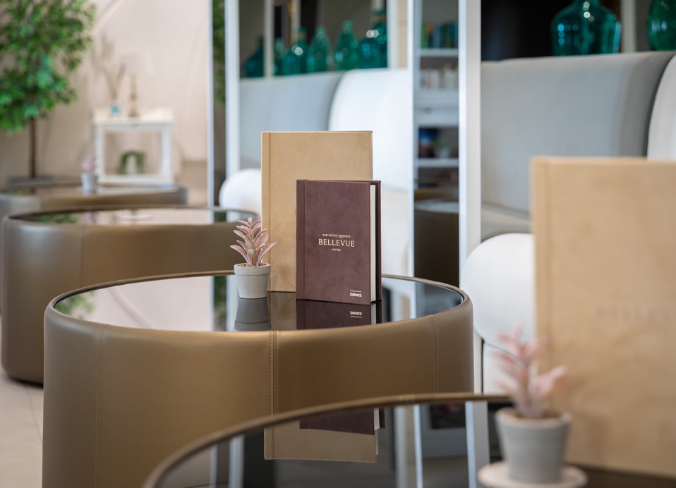 Table in Bar Noir at Younique Bellevue Hotel by Aminess with a menu and small plant.