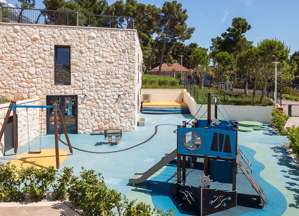 Outdoor-Spielplatz für Kinder mit Rutschen und Schaukel im Aminess Laurel Khalani Hotel.