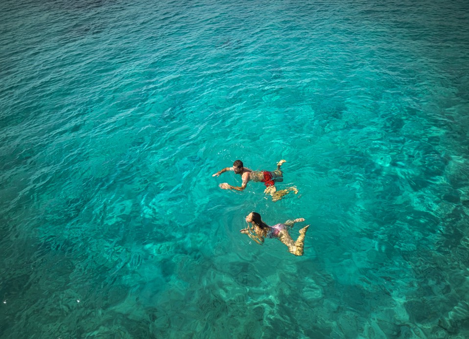 People swimming in the beautiful turquoise waters near Port9 Planet Camping by Aminess.