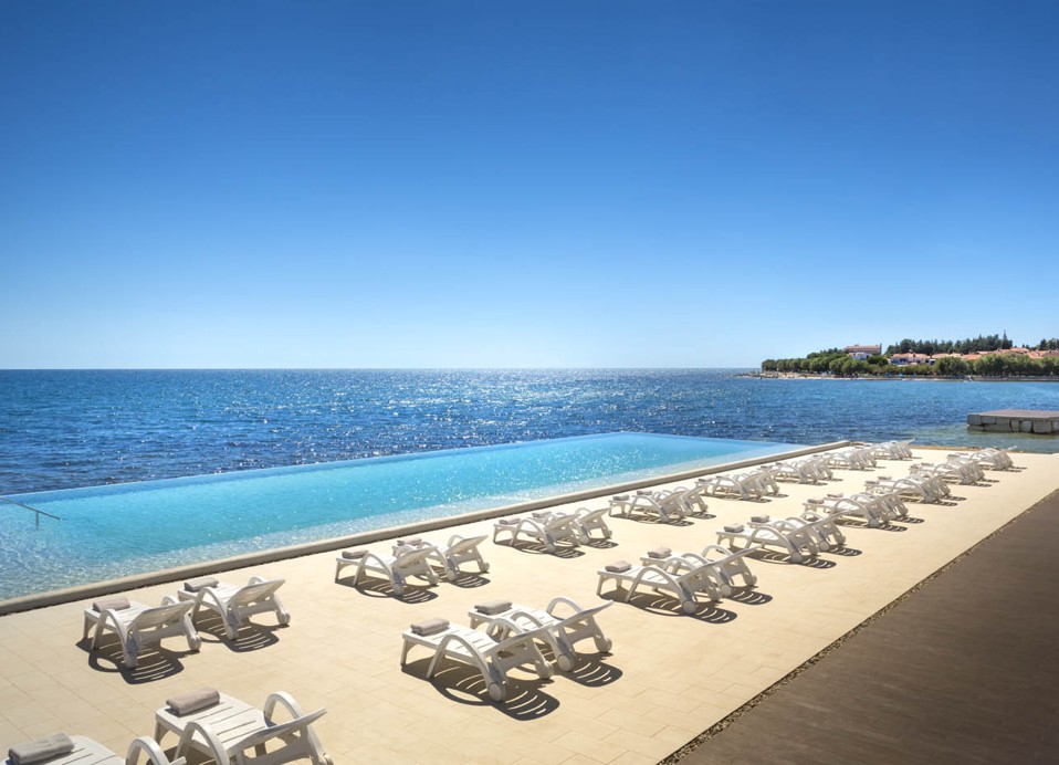 Postavljanje ležaljki kraj infinity bazena s pogledom na more i Novigrad.