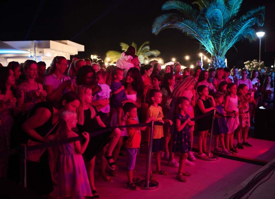 Kinderen en ouders in het publiek kijken naar het avondprogramma.