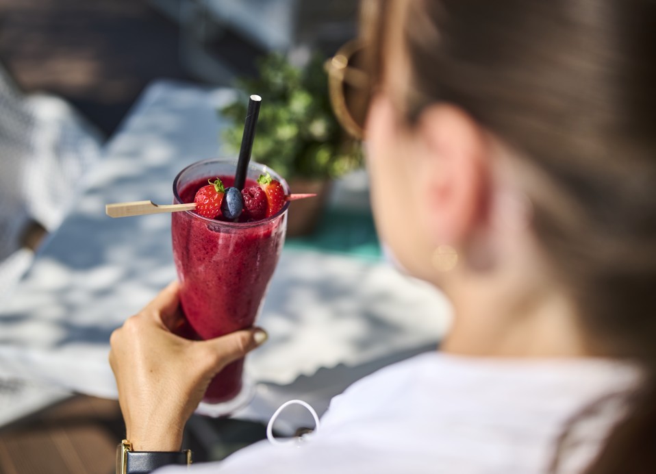 Frau genießt einen fruchtigen Smoothie an der Pool Bar Frullie innerhalb des Resorts, in der Nähe von Aminess Vival Port9 Residence, Korcula, mit einer entspannten Atmosphäre im Hintergrund.