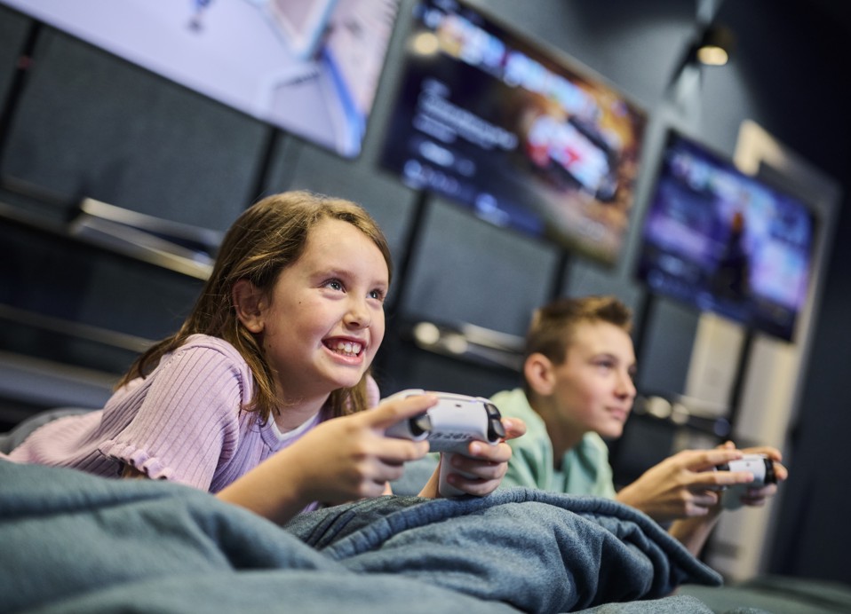Kinderen spelen videogames met controllers in de gamingruimte van het hotel