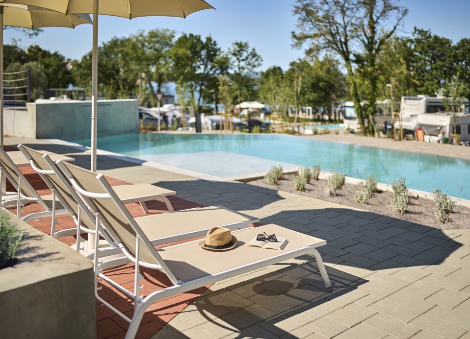 Piscina a sfioro con lettini e ombrelloni con vista sull’area campeggio dell'Aminess Style Camping Atea Resort.