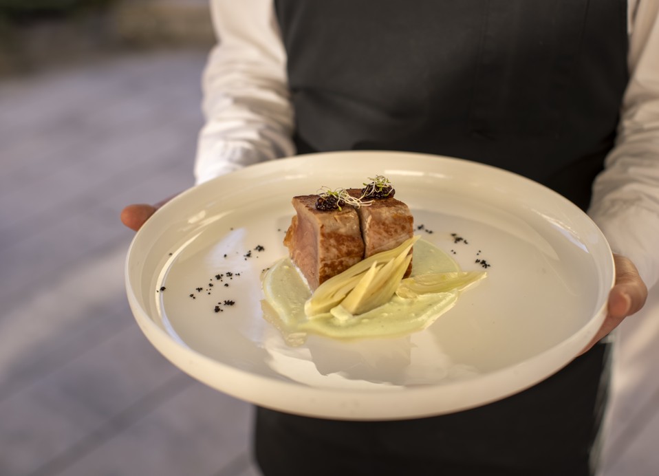 Cameriere che presenta un piatto gourmet al ristorante 7 Seas a Korcula, con una bistecca di tonno scottata servita su un letto di salsa cremosa.