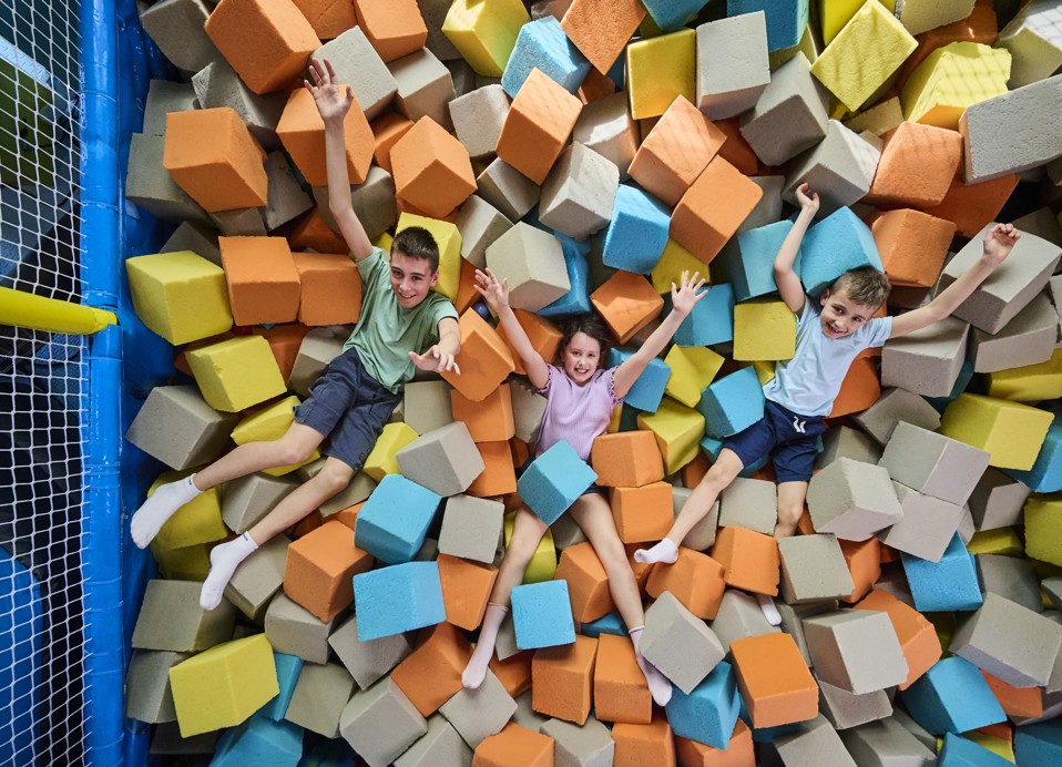 Kinderen spelen en springen in een bak met schuimblokken in een speelruimte