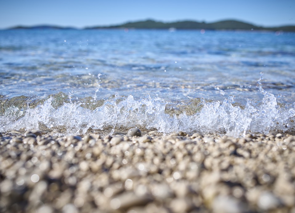 Nahaufnahme von sanften Wellen, die über Kieselsteine am Strand bei Aminess Vival Grand Azur in Orebic spülen.