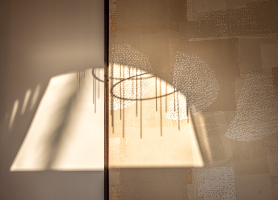 Sunlit chandelier shadow on wall art at Aminess Younique Korcula Heritage Hotel.