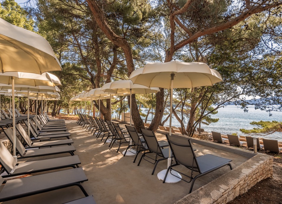 Relaxing on loungers under parasols by the sea at Aminess Younique Senses Resort Hvar