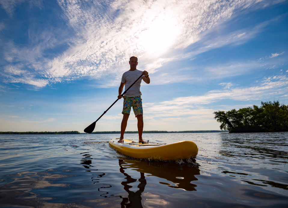 Ein Gast genießt Stand-Up-Paddleboarding unter einem klaren Himmel in der Nähe von Aminess Style Camping Atea Resort.