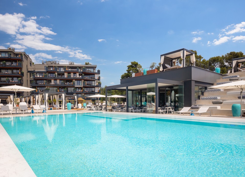 Outdoor pool with sun loungers and parasols at Aminess Younique Vollo Hotel Residences