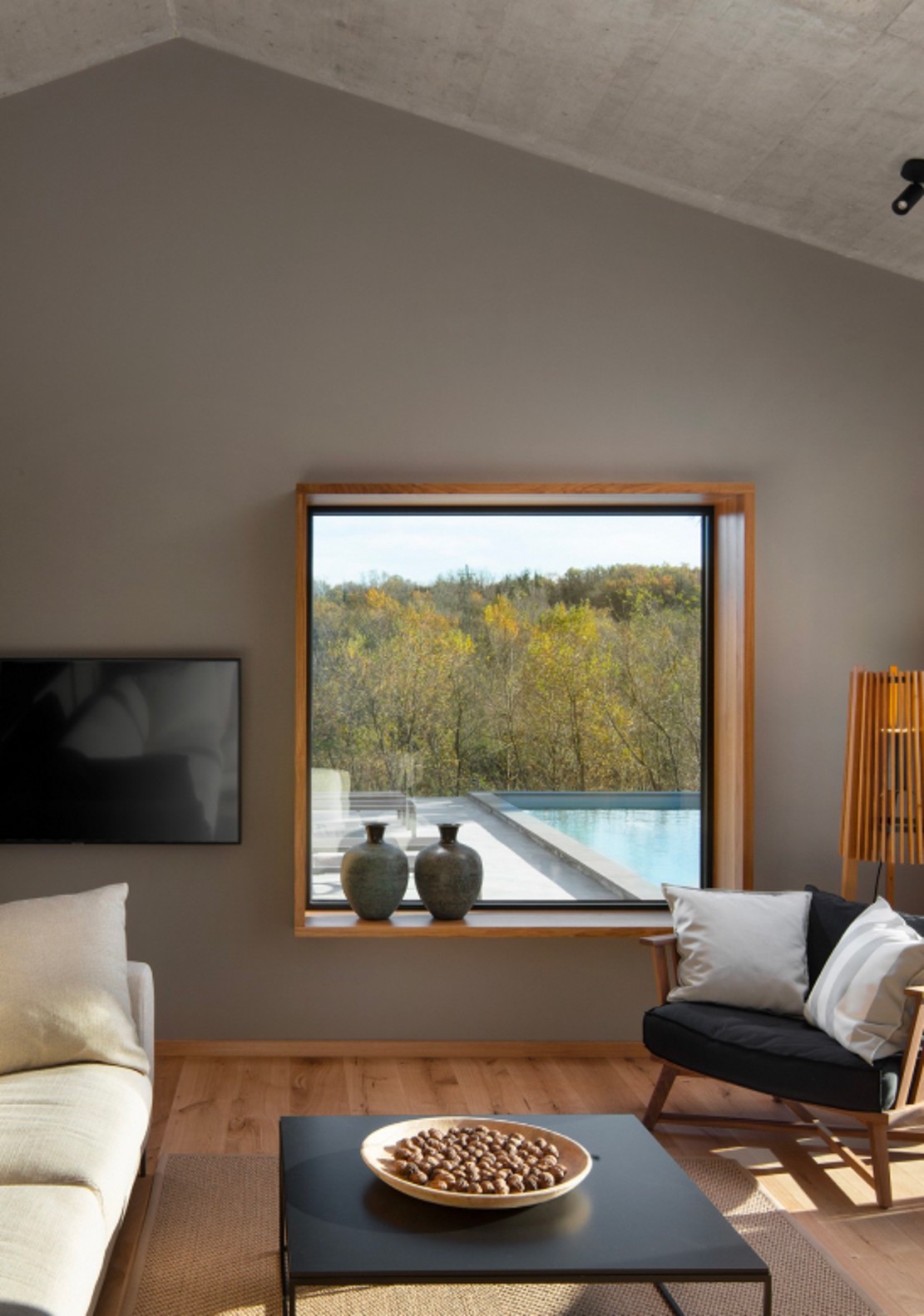 Moderna dnevna soba s udobnim kaučem i velikim prozorom koji gleda na područje s bazenom