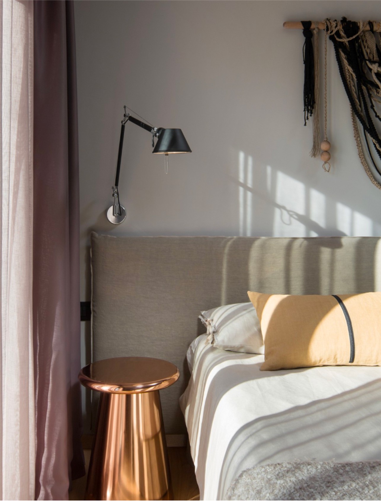 A double bed with a neatly arranged white sheet and a stylish lamp above the bedside table.