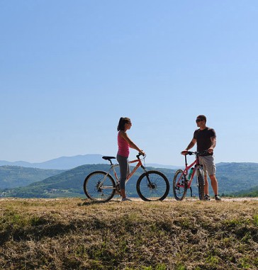 A couple standing on a hill next to their bikes with the Istrian countryside in the background